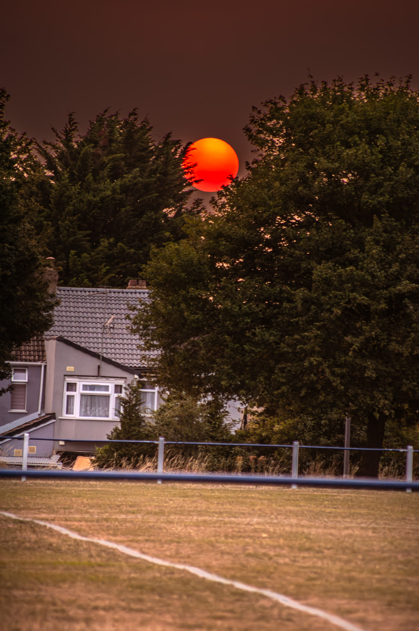 Sun’s disc fading into orange haze during Luton sunset after UK heatwave
